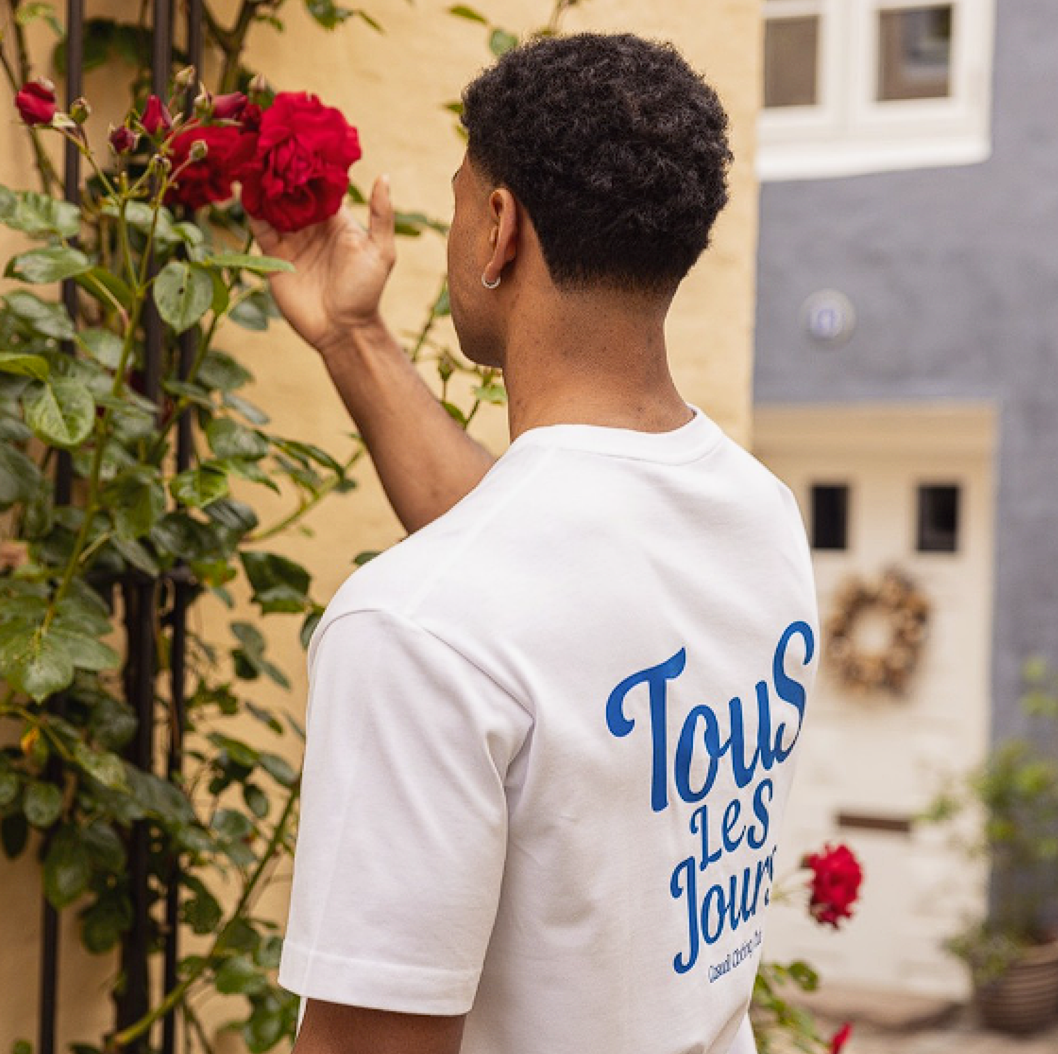 Fotos taget af Marketisr for Casual Appeal. Modellen står med ryggen til og viser trøjens bagside. Flotte æstetiske blomster i baggrunden.